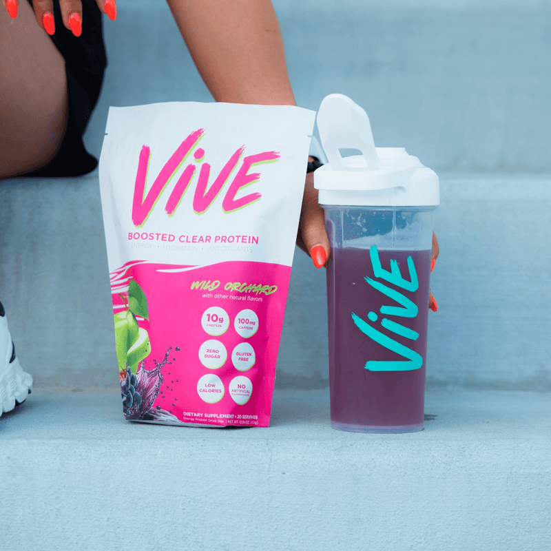 Vive protein powder package and shaker cup with purple liquid on a light blue background. Protein shakes