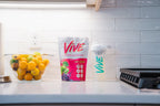 Vive wild orchard protein powder package and container on a kitchen counter with fruits in the background. Best Protein Powder