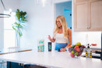 Woman scooping Vive clear protein in to shaker bottle on a kitchen counter