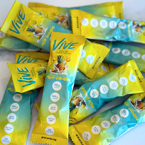 Vive Piña Colada flavor clear protein powder stick packs with pineapple flavor on a white countertop. Protein Shakes