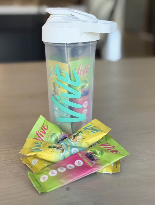 Vive protein shaker bottle with protein powder stick packs on a wooden surface. Protein Shakes